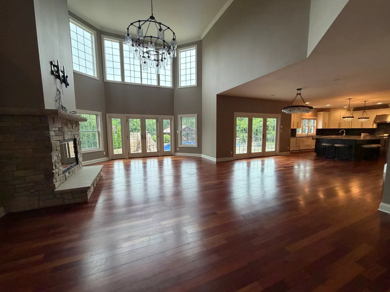 Finished great room with wood floors, tall windows and the kitchen beyond