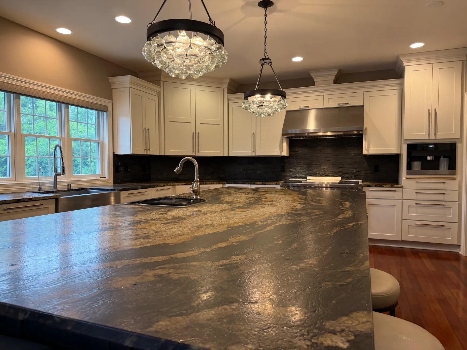 Open kitchen with glass chandeliers and stone island, detailed during a Star Pro move-out clean
