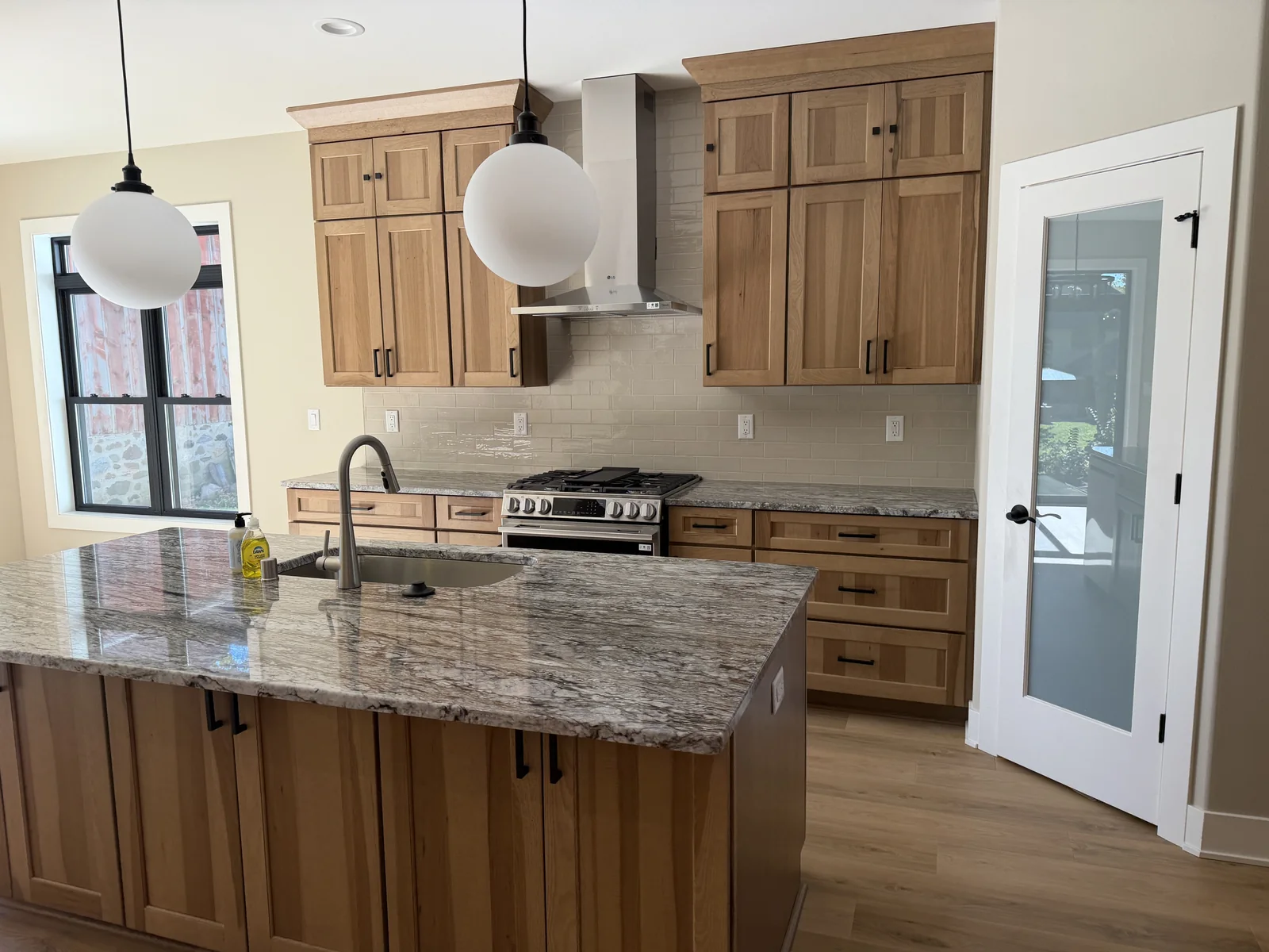 Newly built kitchen with a stone island, wood cabinets and stainless range