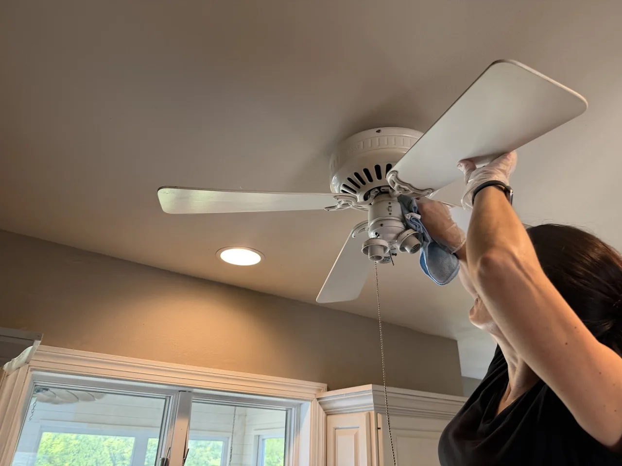 Star Pro team member wiping down ceiling fan blades during a detail clean