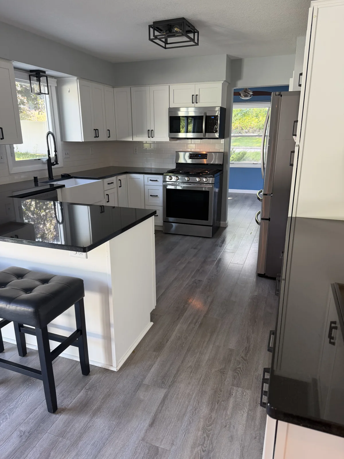 Residential kitchen with white cabinetry, black countertops and stainless appliances